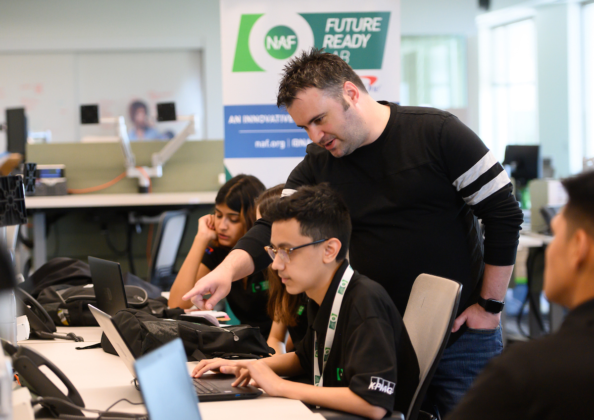 A volunteer helps NAF students navigate their hands-on learning project